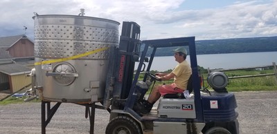 Winemaker Vinny Aliperti driving a wine tank on a forklift.