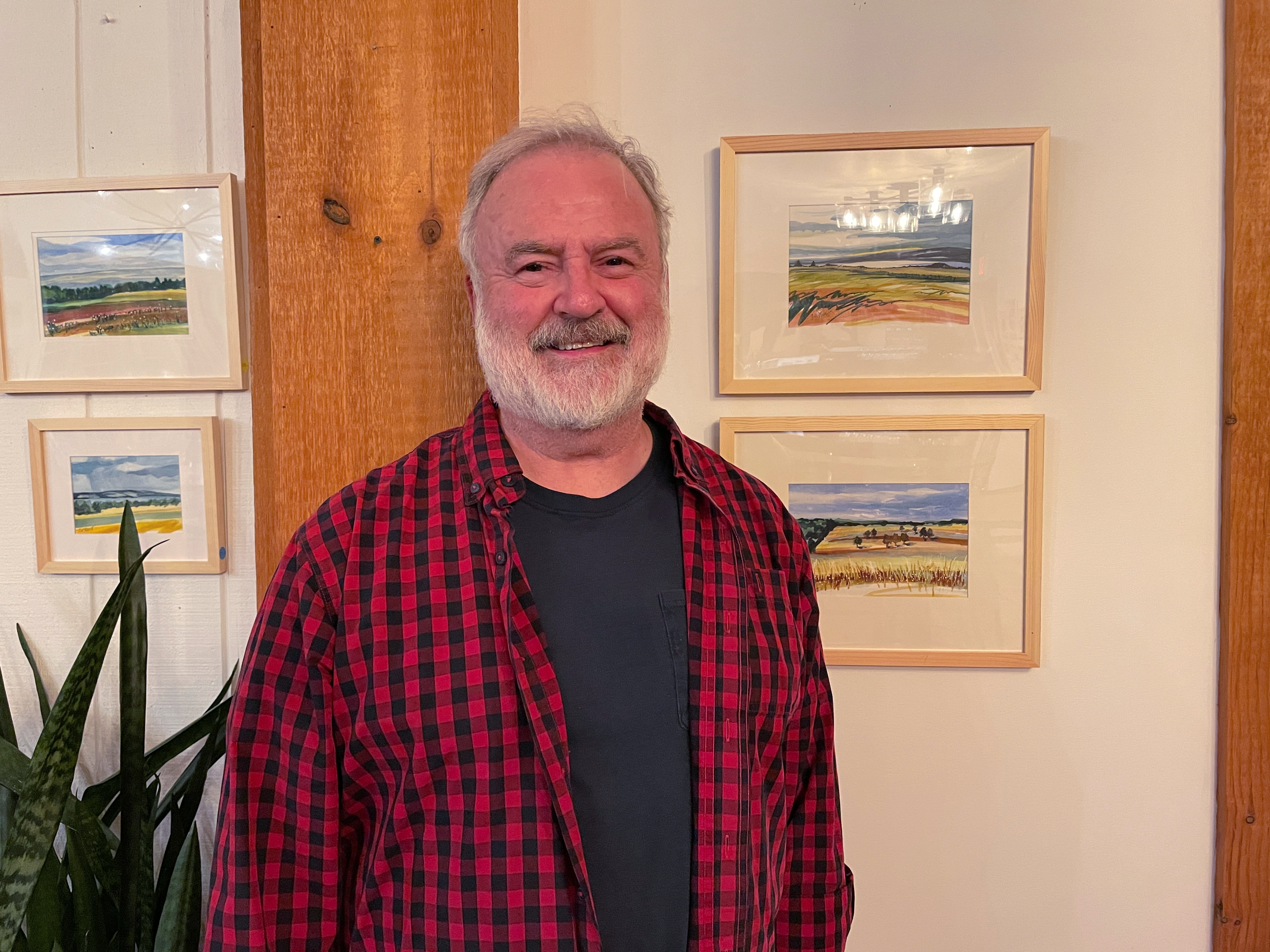 John Nyquist in front of his Finger Lakes Series watercolor paintings